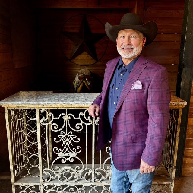 Mike Flores wearing a cowboy hat and purple blazer at a Texas-style venue